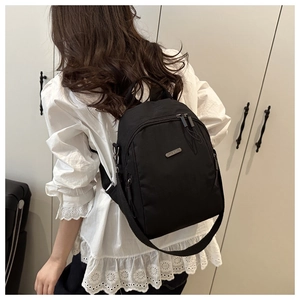 Model wearing a black mini waterproof nylon backpack with an adjustable shoulder strap