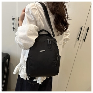 Dettaglio di uno zaino minimalista in nylon nero con una placca logo in metallo argento