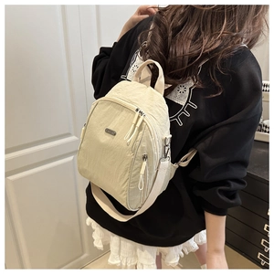 Detail of beige nylon backpack showing high-density texture and zip pockets on model