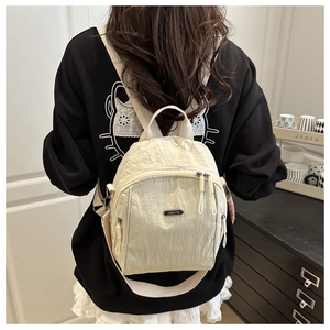 Beige lightweight pleated nylon backpack with multiple zipper pockets shown on model