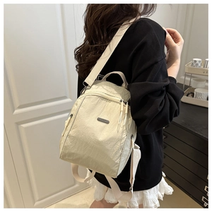 Detail of off-white nylon backpack showing wrinkled texture and adjustable shoulder strap