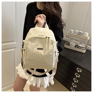 Detail of the cream nylon backpack featuring crinkled texture and metal brand plaque