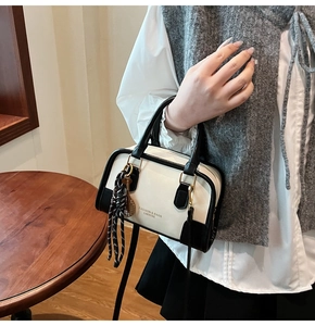 Detail of black and white Boston bag with leather tassels and a tennis racket charm