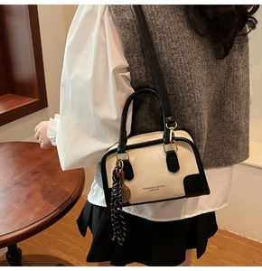Detail of cream and black Boston bag with fashion logo and tennis racket charm accessory