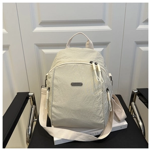 Detail of cream nylon multi-compartment backpack with brand plaque on modern chair