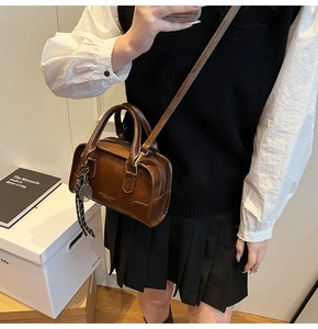 Brown vintage Boston bag with top handles, crossbody strap and silver badminton charm
