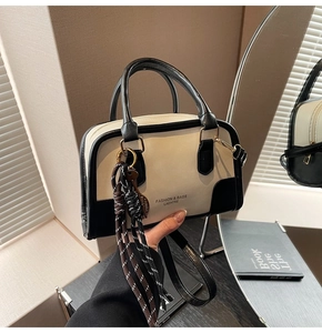 Detail of black and white handbag with logo print and decorative leaf pendant