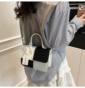 Detail of minimalist black and white patchwork handbag with gold metal buckles and strap