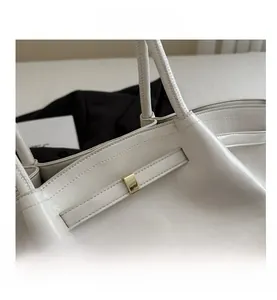 Detailansicht der cremeweißen Ledertasche mit feiner Textur und goldener Metallschnalle
