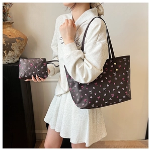 Dettaglio della borsa shopper marrone scuro con fiocchi rosa e motivi floreali su pelle PU