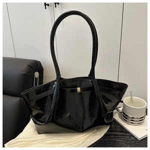 Detail der glänzenden schwarzen Falten-Tote-Bag mit goldener Hardware auf Seide