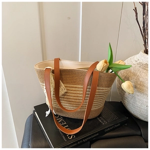 Detail of woven straw tote bag with brown leather straps and white lace bow accessory