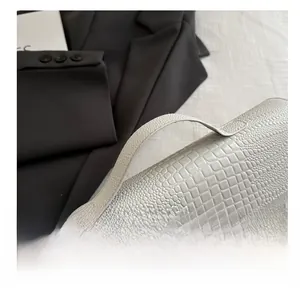 Detail of white crocodile texture leather handbag with vintage gold metal clasp