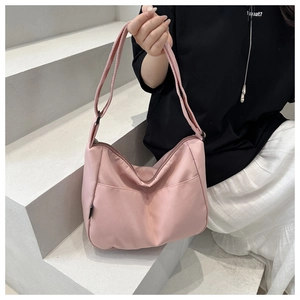 Pink nylon hobo crossbody bag featuring adjustable strap and front pocket detail