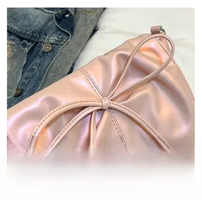 Gros plan sur un sac sous le bras rose nacré avec un grand nœud décoratif et coutures fines