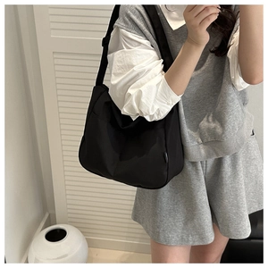 Waterproof black nylon shoulder bag with side pocket and strap shown on a model