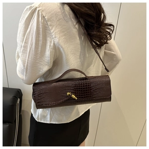 Detail of dark brown faux-crocodile cylindrical bag with gold-tone twist-lock closure