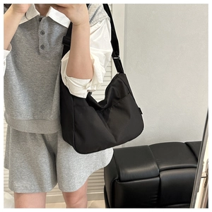 Mirror selfie showing the black nylon crescent crossbody bag with adjustable wide strap