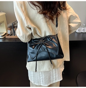 Détail d'un sac bandoulière en cuir PU noir avec un grand nœud porté par un mannequin