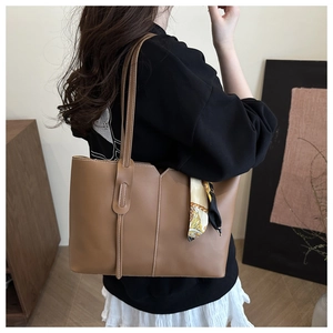 Detail of caramel tote bag featuring contrast stitching and decorative silk scarf accent