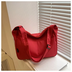 Detail of red nylon shoulder bag showing zipper closure and adjustable black strap buckle
