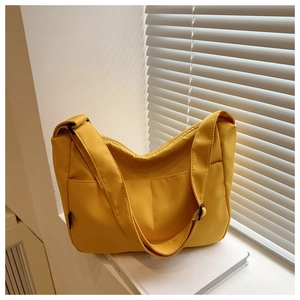 Detail of bright yellow nylon crossbody bag with multi-pocket design on white books