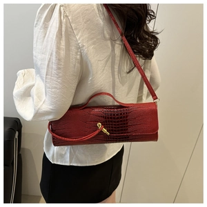 Detail of red crocodile pattern handbag with golden cone twist lock and sleek leather texture