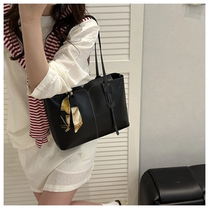 Detail of black matte leather tote bag with white stitching and decorative silk scarf