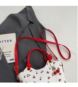 Détail d'un sac seau rétro blanc à motif cerise avec anse anneau rouge et bandoulière