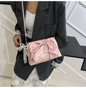 Détail du sac rose avec grand nœud en cuir, breloque en perles et ornement dentelle