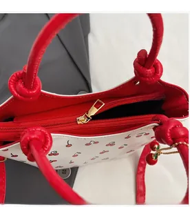 Détail de la fermeture éclair en métal et de l'imprimé cerise sur un sac blanc élégant