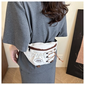 Détail du sac banane en toile blanche avec bordures brunes et poche à cordon