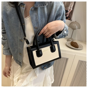 Detail of minimalist black and beige contrast crossbody bag worn with a casual denim outfit