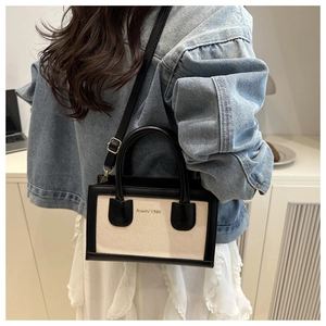 Close-up of stylish canvas tote bag with black trim worn by model in casual outfit