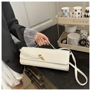 Detail of white crocodile pattern shoulder bag with a gold knot-shaped metal clasp