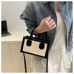 Détail du sac à bandoulière en toile et cuir noir porté par un mannequin en style décontracté