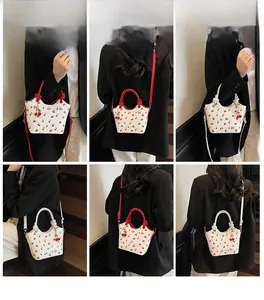 Détail du sac seau imprimé cerises avec bandoulière rouge et pendentif cerise mignon