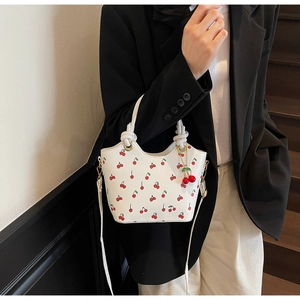Détail du sac cabas blanc à imprimé cerises avec pendentifs 3D sur un blazer noir