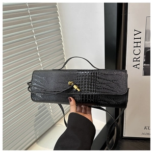 Detail of black crocodile pattern leather handbag with gold twist lock and shoulder strap