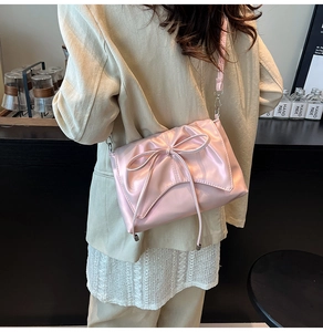 Détail du sac bandoulière rose clair avec nœud décoratif, fini brillant et métal argent