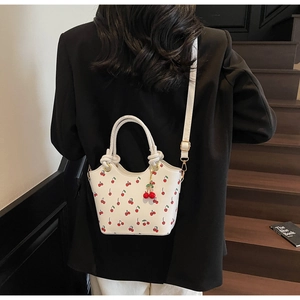 Détail du sac blanc avec imprimé cerise et poignée en corde torsadée élégante