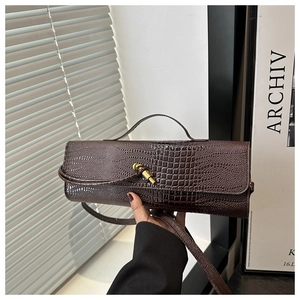 Detail of dark brown croc-effect handbag with vintage gold knot clasp and slim handle