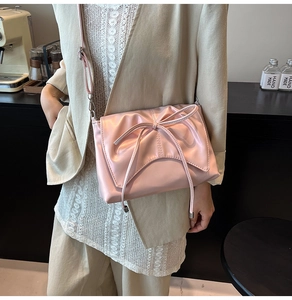 Vue détaillée d'un sac bandoulière rose avec un grand nœud sur une sangle en cuir