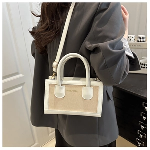 Détail du sac bandoulière tissé beige avec garniture en cuir blanc porté avec un costume