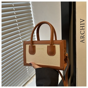 Detail of a vintage canvas handbag with brown leather trim and gold brand lettering