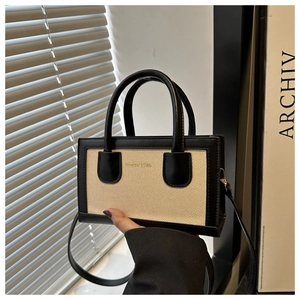 Detail of vintage tote bag with black leather trim, woven fabric, and SINCE 1985 text