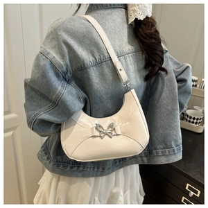 Détail d'un sac porté épaule blanc en demi-lune avec boucle papillon argentée sur un mannequin