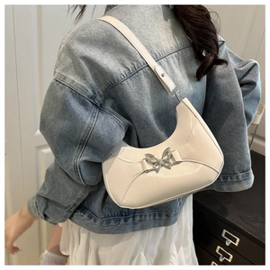 Détail d'un sac sous le bras blanc en forme de croissant avec boucle papillon métallique