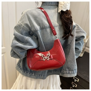Détail du sac hobo rouge brillant avec ornement papillon argenté et bandoulière réglable