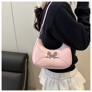 Détail du sac croissant en cuir verni rose avec boucle papillon argentée sur l'épaule